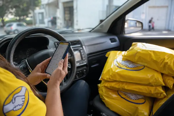 Entregadora conferindo no celular o valor da rota antes de aceitar